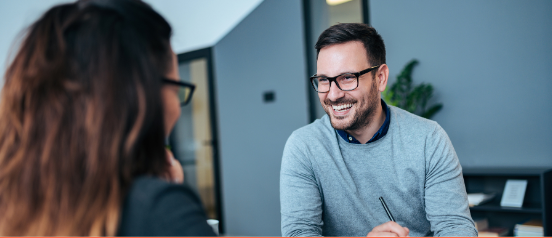 A young man smiling whilst in an interview for an IT Consulting Position