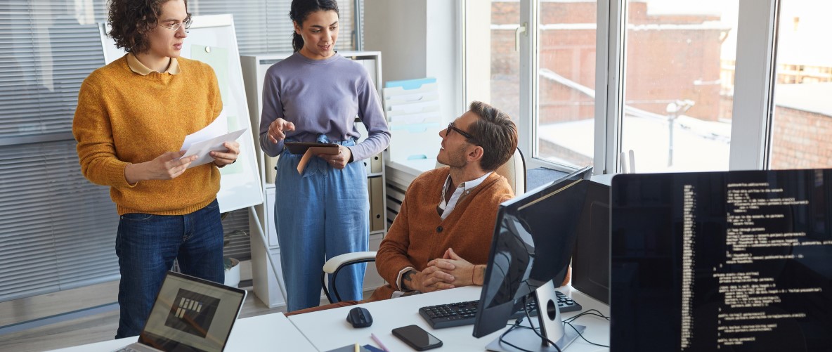 A Group of Diverse Adults in an IT Office Setting, discussing projects and completing tasks