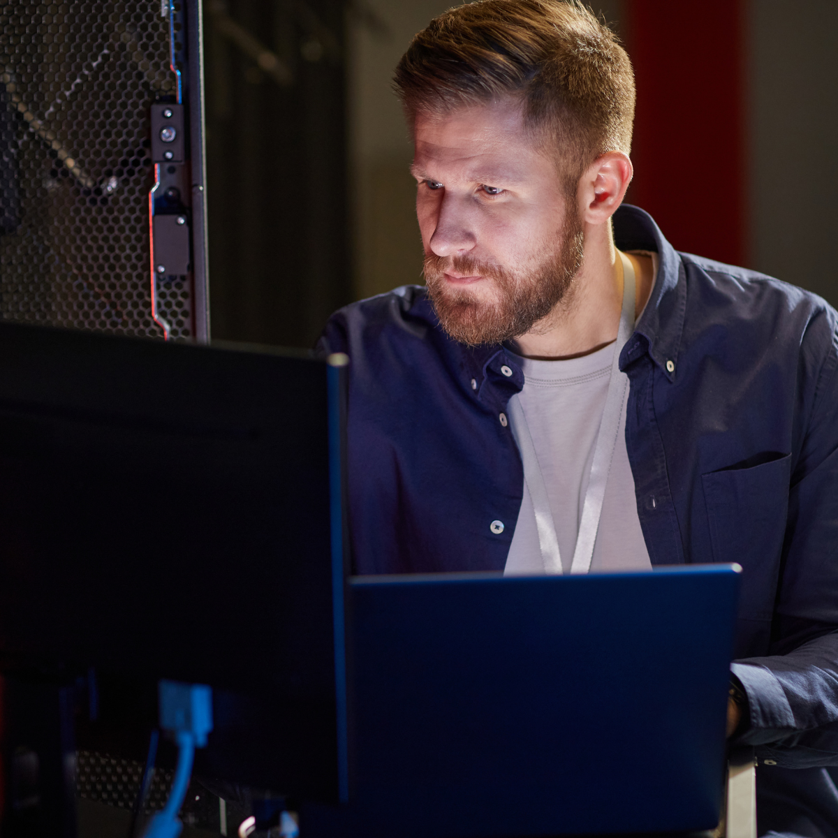 IT Projects Engineer configuring systems using a laptop beside server equipment